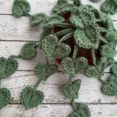 a crocheted pot holder with green leaves on the top and bottom, sitting on a white wooden surface