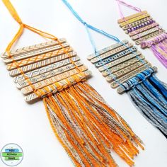 three necklaces with different colored tassels and beads hanging from the side on a white surface