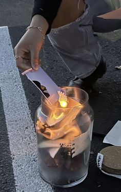 a person cutting paper with a knife in a glass vase filled with water and fire