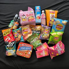 a pile of snacks sitting on top of a black cloth covered table next to a bag of chips