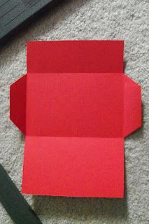 an open red box sitting on the floor next to a pair of scissors and a piece of paper