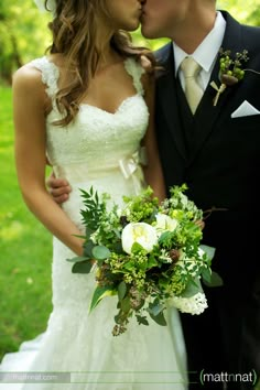 a bride and groom kissing each other outside