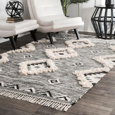 a white chair sitting on top of a wooden floor next to a black and white rug