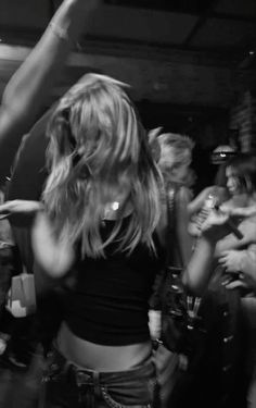 black and white photograph of woman dancing in front of other people at a club or bar