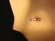 a woman's stomach with a tiny pink teddy bear dangling from the middle part of her belly