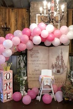 pink and white balloons are on the stage for a princess themed birthday party at disney's castle