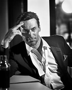 a man in a suit and tie sitting at a table with his hand on his head