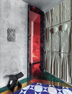 an artisticly designed bathroom with colorful tiles and floor to ceiling wall panels, along with a black chair