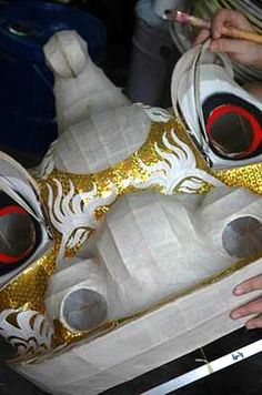 someone is painting an animal mask with gold glitter