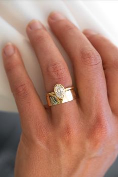 a woman's hand wearing a gold ring with a diamond on the middle finger