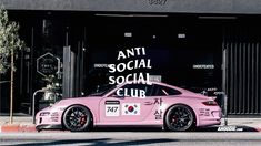 a pink sports car parked on the side of the road in front of a building