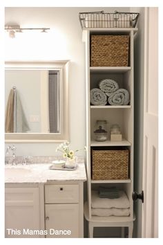 a white bathroom with towels and baskets on the shelves