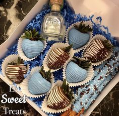 four chocolate covered strawberries in a box with a bottle of patron liqueur