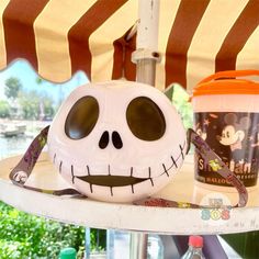 a halloween decoration with a jack skellingy face and drink on a table under an umbrella