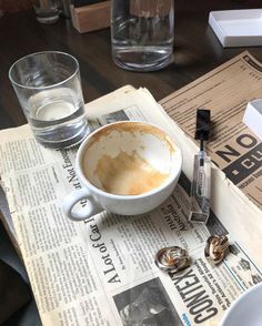 a cup of coffee sitting on top of a newspaper