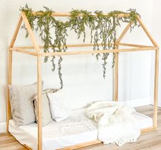 a bed with plants growing over it in a room that has wood floors and white walls