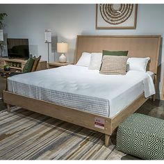 a bedroom with a bed, chair, and ottoman in front of a tv on the wall