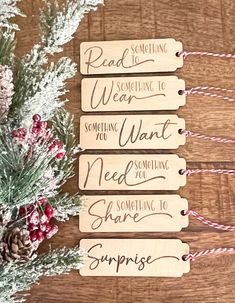 three wooden tags with writing on them sitting next to some pine cones and evergreen branches