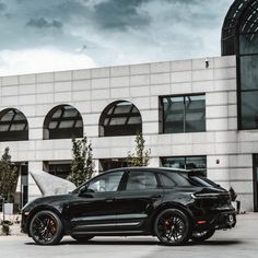 a black porsche cayen is parked in front of a building