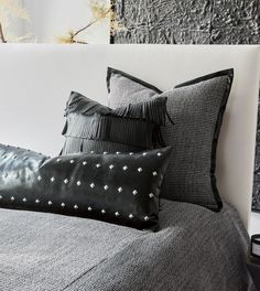 a black and white bed with two pillows on it's headboard next to a plant