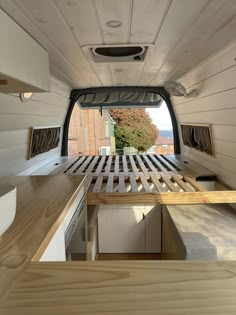 the inside of a camper with wood flooring and white walls, looking out into the kitchen