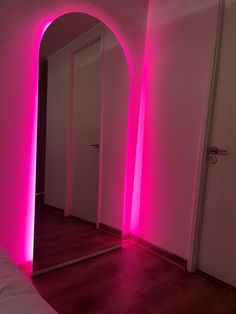 a room with pink lighting and a mirror on the wall next to an open door