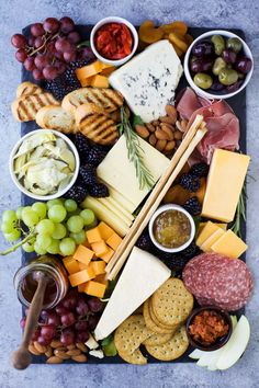 an assortment of cheeses, crackers, grapes and nuts on a platter