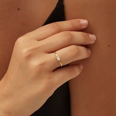 a woman's hand with a gold ring on her left side and the other half of her body behind her