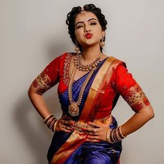 a woman in a red and blue sari with her hands on her hips, posing for the camera