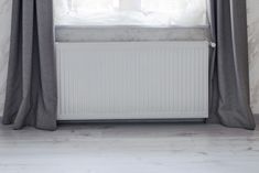 a white radiator sitting next to a window with curtains on top of it