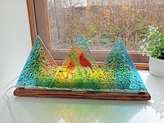 a colorful glass sculpture sitting on top of a table next to a potted plant