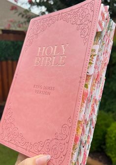 a person holding a pink bible in their hand