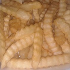 a pile of french fries sitting on top of a white plate