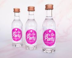 three bottles with pink labels on them sitting next to each other