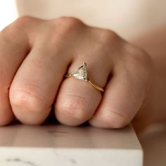 a woman's hand with a diamond ring on top of her finger, sitting on a marble surface