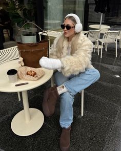 a woman sitting at a table wearing headphones and holding a brown purse with her right hand