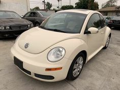 a white volkswagen beetle parked in a parking lot next to other black and gray cars