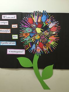 a flower made out of handprints on a bulletin board with words written below it