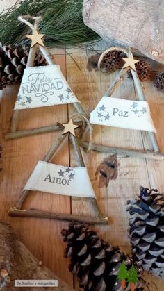 three wooden christmas trees with pine cones and evergreen branches in the middle, on top of a wood table