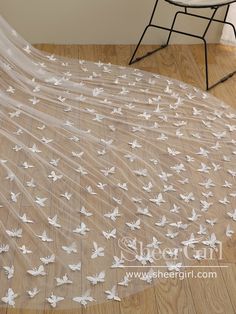 a veil with white butterflies on it is sitting on the floor next to a chair