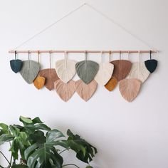 the wall hanging is decorated with different colored leaves and has a plant in front of it