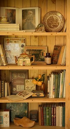 a bookshelf filled with lots of books next to a vase and other items