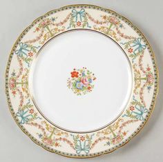 an antique china plate with flowers and bows on the rim, decorated with gold trim