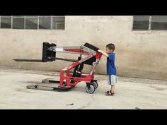 a young boy standing next to a red cart