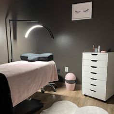 a white bed sitting next to a dresser in a bedroom under a large light fixture