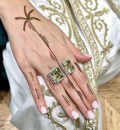 a woman's hand with two rings on it, and a palm tree tattoo