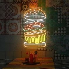 a neon sign that has a burger on it in front of a wall with tiles