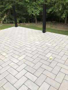 a brick patio with black posts and trees in the background