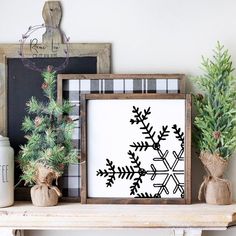 a wooden frame with a snowflake pattern is sitting on a mantle next to potted plants