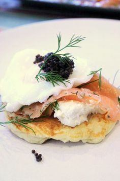 a white plate topped with pancakes covered in cream cheese and salmon